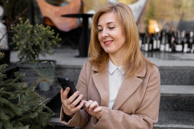 Feliz mujer de mediana edad comprobando su teléfono