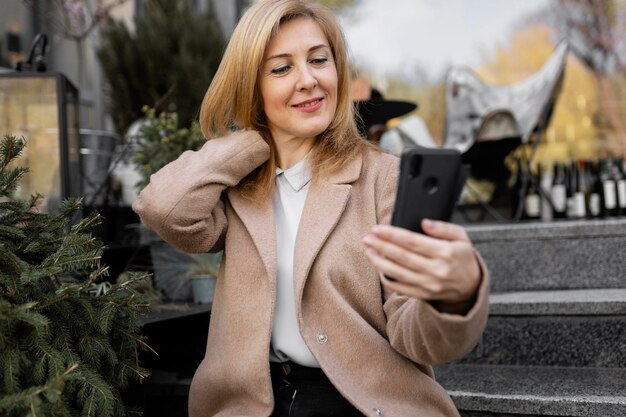 Feliz mujer de mediana edad comprobando su teléfono