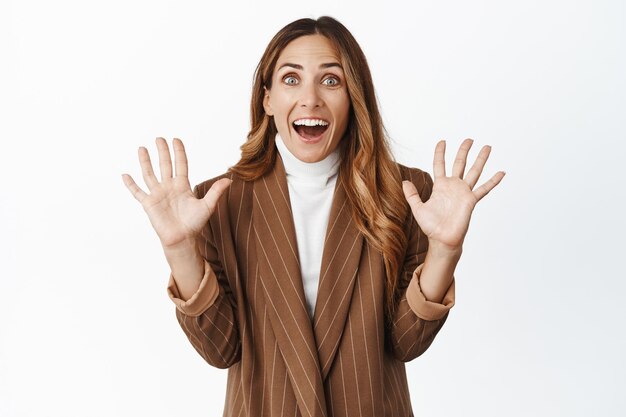 Feliz mujer de mediana edad mirando sorpresa levantando las manos con expresión entusiasta sonriendo con alegría fondo blanco.