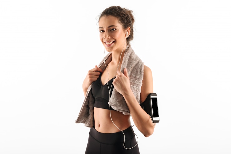 Foto gratuito feliz mujer morena fitness rizada con toalla escuchando música