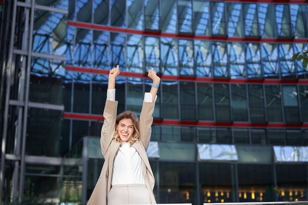 Feliz mujer de negocios bailando en la calle levantando las manos mujer corporativa celebra su victoria o éxito