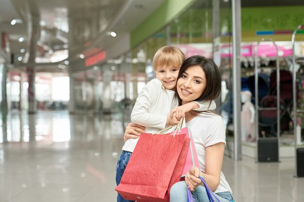Feliz mujer y niña en posando, sonriendo en el centro comercial.