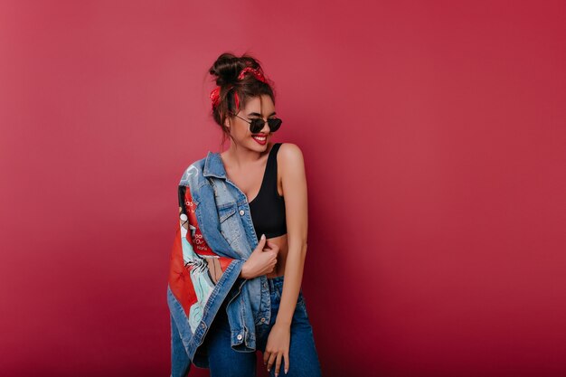 Feliz mujer de pelo oscuro viste ropa de mezclilla pasar tiempo en sesión de fotos