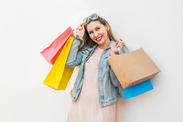 Foto gratuita feliz mujer de pie con bolsas de compras en la pared de luz