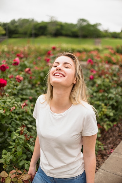 Feliz mujer de pie en el jardín de flores