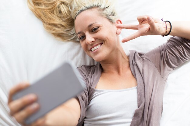 Feliz mujer posando con gesto de cuerno para selfie