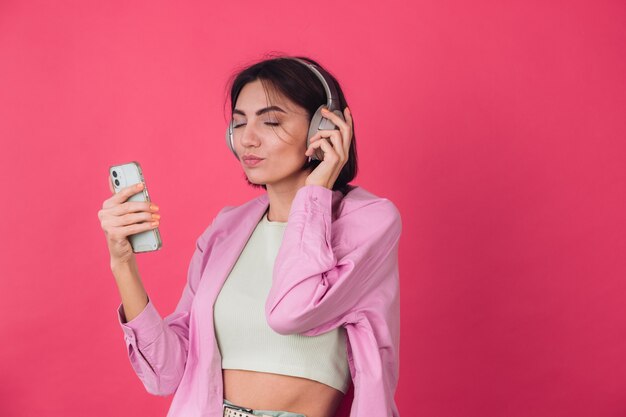 Feliz mujer positiva en auriculares en la pared roja rosa