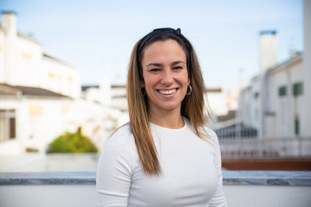 Feliz mujer positiva posando en el balcón del apartamento