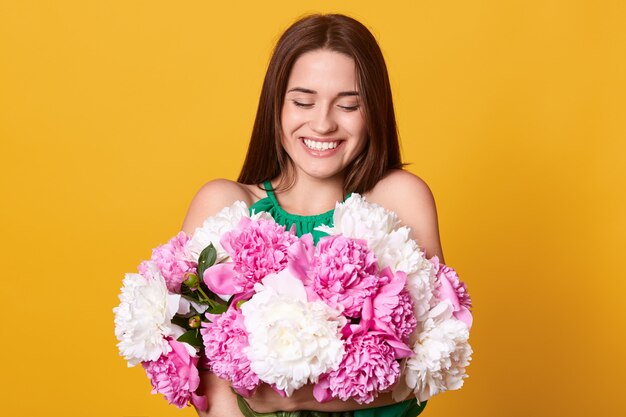 Feliz mujer recibe flores del esposo, mirando su regalo con una sonrisa encantadora