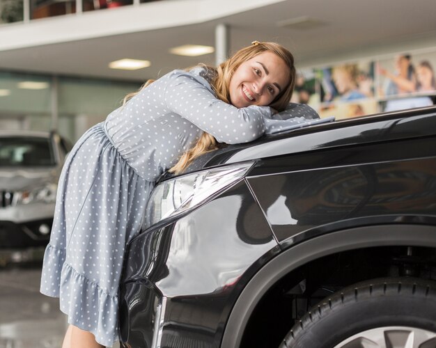 Feliz mujer rubia abrazando un coche