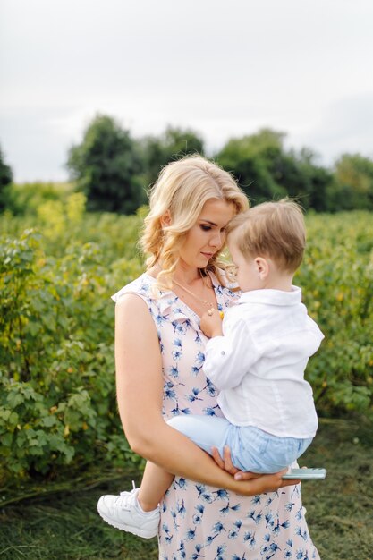 Feliz mujer rubia y lindo niño parado en el jardín de verano