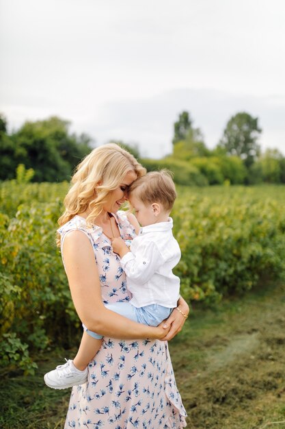 Feliz mujer rubia y lindo niño parado en el jardín de verano