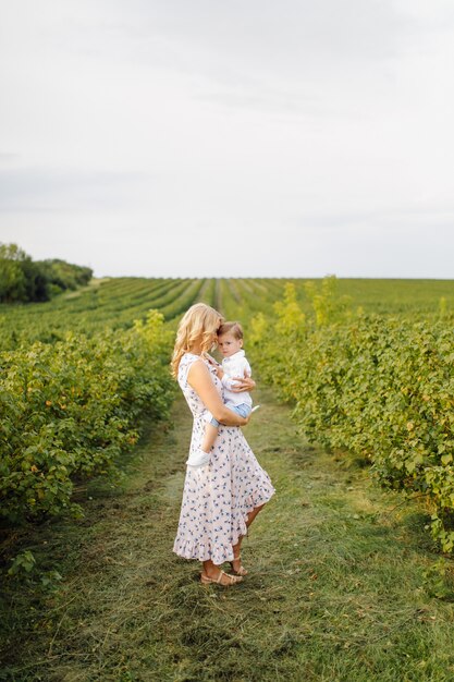 Feliz mujer rubia y lindo niño parado en el jardín de verano