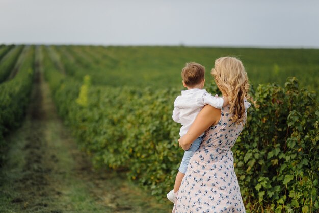 Feliz mujer rubia y lindo niño parado en el jardín de verano