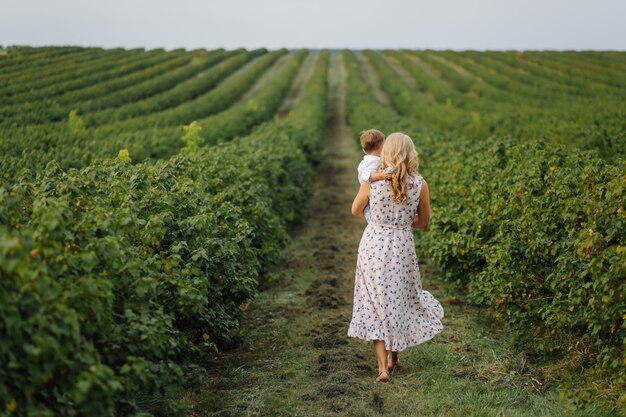 Feliz mujer rubia y lindo niño parado en el jardín de verano