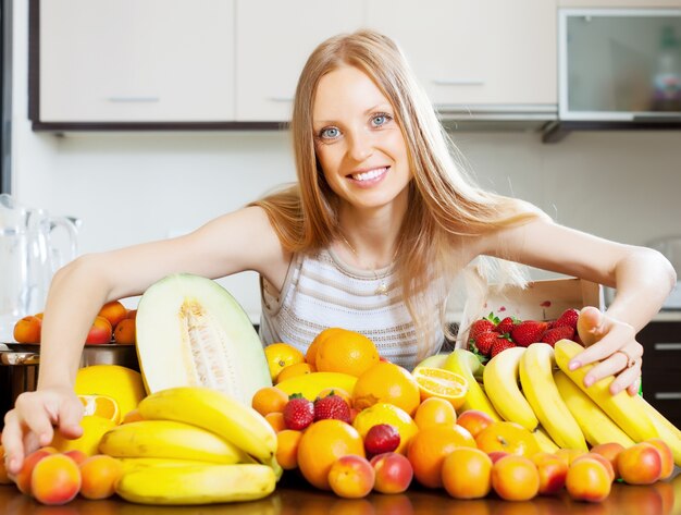 Feliz mujer rubia con montón de frutas