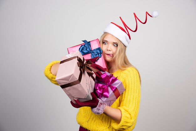 Feliz mujer rubia en suéter amarillo con regalos de Navidad.