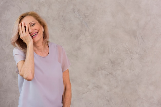 Feliz mujer senior cubriendo su ojo con la mano