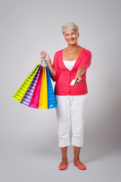 Feliz mujer senior pagando compras con tarjeta de crédito