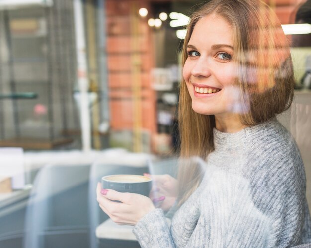 Feliz mujer sentada con café