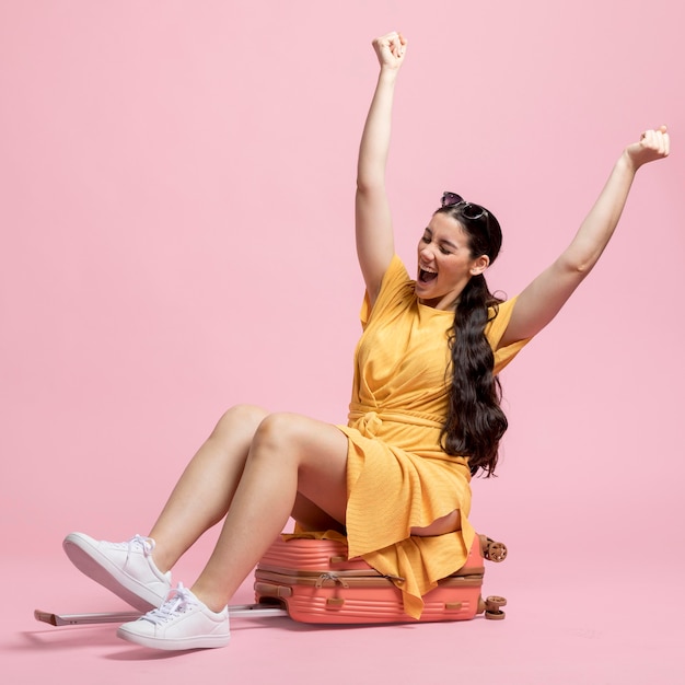 Foto gratuita feliz mujer sentada en el equipaje