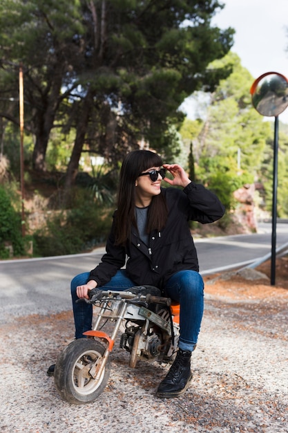 Feliz mujer sentada en una motocicleta pequeña