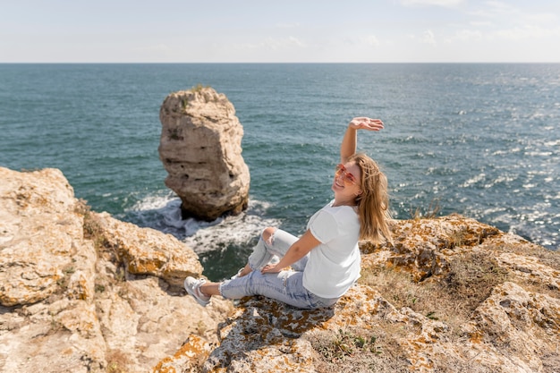 Feliz mujer sentada sobre las rocas
