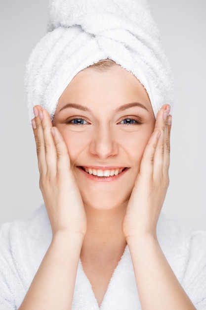 Feliz mujer sonriente aplicar crema facial, concepto de cuidado de la piel