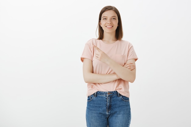 Feliz mujer sonriente mostrando promo, apuntando hacia la esquina superior izquierda