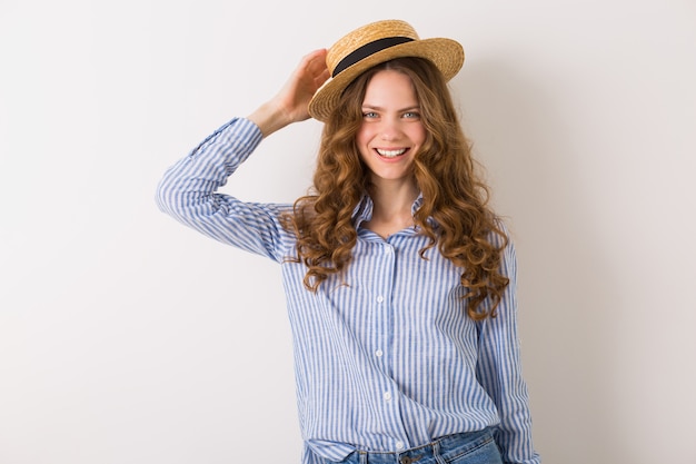 Feliz mujer sonriente posando con sombrero de paja en blanco