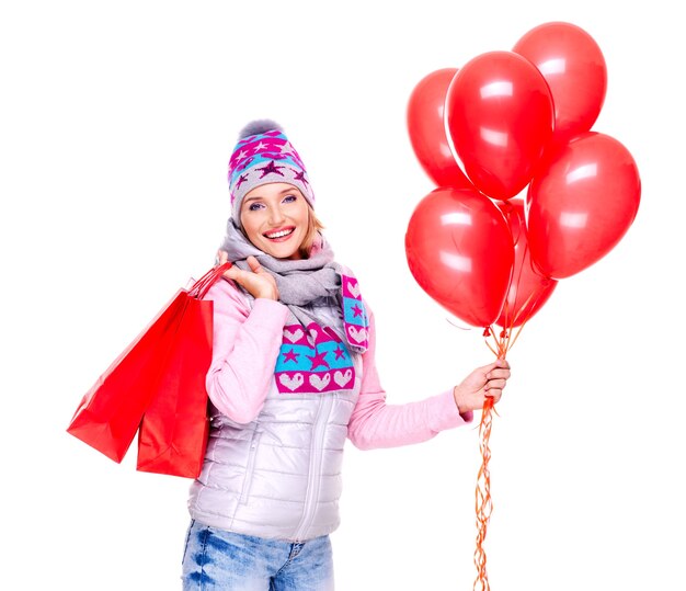 Feliz mujer sonriente con regalos y globos rojos después de ir de compras aislado en blanco