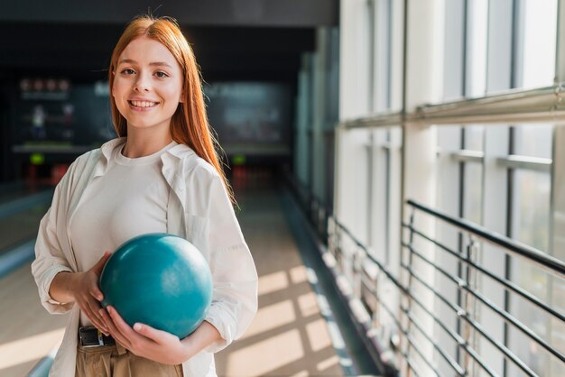 Feliz mujer sosteniendo una bola de bolos turquesa