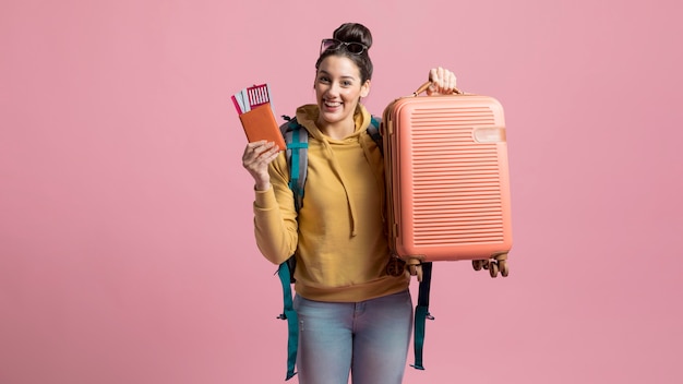 Feliz mujer sosteniendo su equipaje y boleto de avión