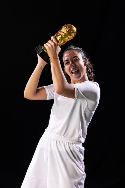 Feliz mujer sosteniendo el trofeo de fútbol