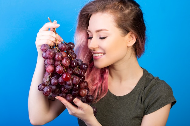 Feliz mujer sostiene un gran racimo de uvas con ambas manos