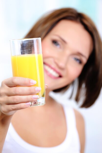 Feliz mujer sostiene un vaso de jugo de naranja