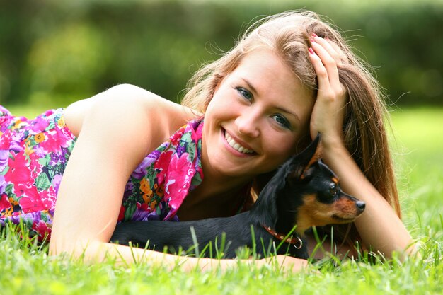 Feliz mujer tumbada en la hierba con su perro