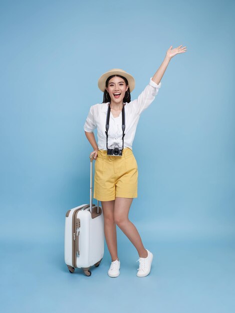 Feliz mujer turista asiática sosteniendo el equipaje agitando la mano dando la bienvenida y saludando que va a viajar