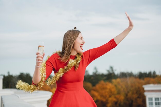 Feliz mujer en vestido rojo de fiesta en la azotea