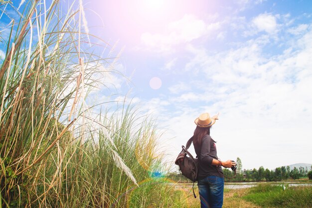 Feliz mujer viajero mirando al cielo azul con campo de hierbas, wanderlust concepto de viaje, el espacio para el texto