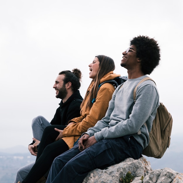 Foto gratuita feliz multi étnica joven pareja sentada en roca disfrutando juntos