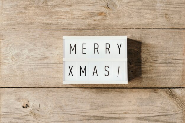 Feliz navidad texto sobre un panel led y fondo de madera