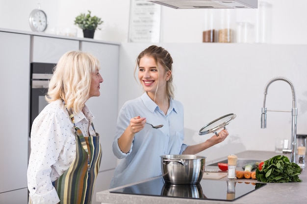 Foto gratuita feliz nieta y su abuela cocinando sopa de verduras