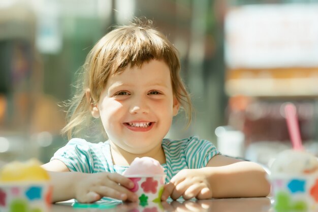 Feliz niña de 3 años comiendo helado