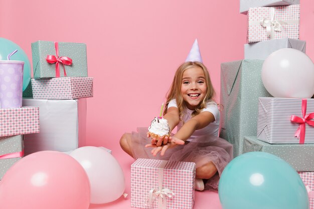 Feliz niña bonita en un sombrero de cumpleaños celebrando