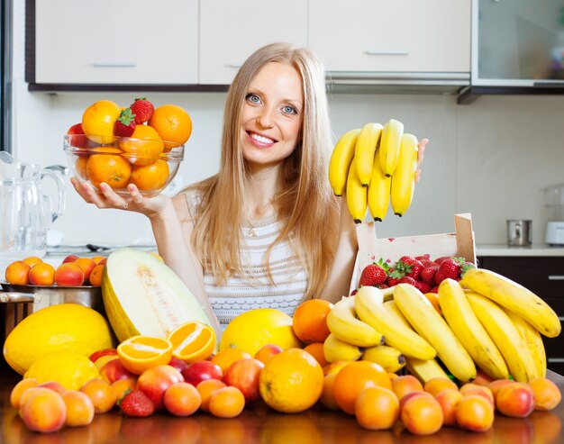 Feliz niña de la celebración de varias frutas en la cocina casera