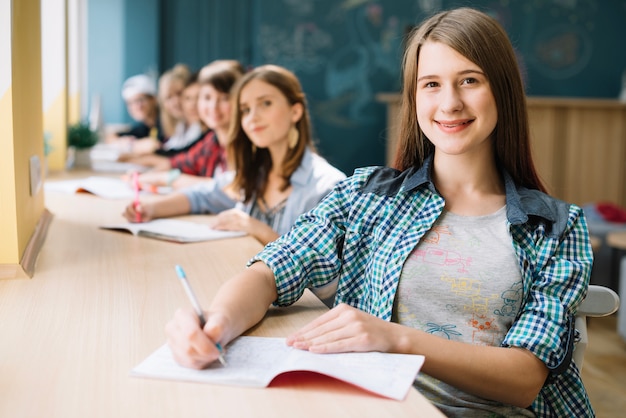 Feliz niña con compañeros de clase en la mesa