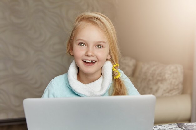 Feliz niña emocionada de apariencia europea sonriendo alegremente