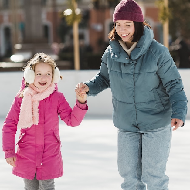 Feliz niña y madre patinaje sobre hielo