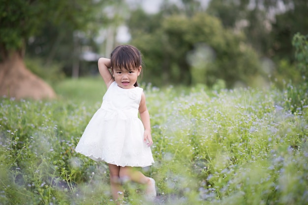 Feliz niña de pie en el prado
